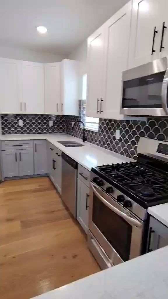New white kitchen with a scalloped black backsplash and quartz counters
